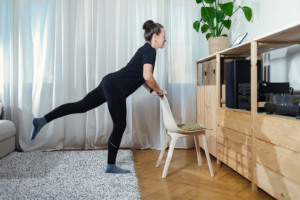 A woman completing exercises in her living room as instructed by the app on her tablet device.