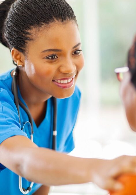 caring african medical nurse comforting senior patient in office